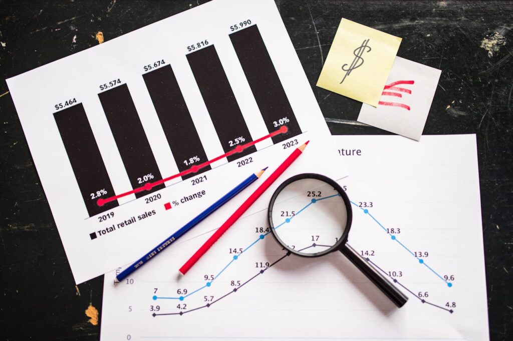 pexels photo 7947758 Charts and graphs highlighting retail sales growth, utilizing a magnifying glass for detail.